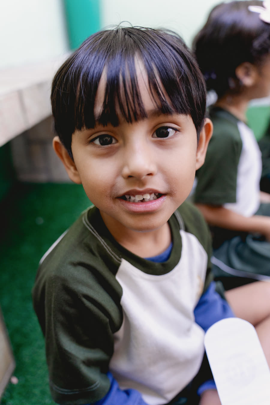 Criança da turma Pré II sorrindo durante atividade na Raízes do Saber